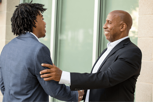 Two men genially talking and shaking hands.