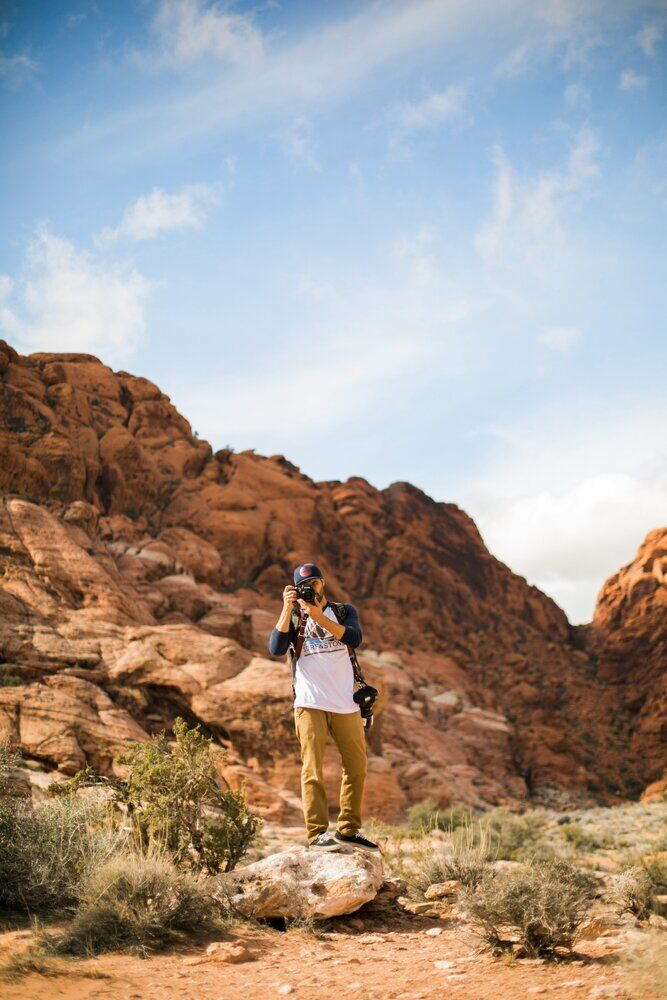 Young man hiking with camera in a rocky canyon.