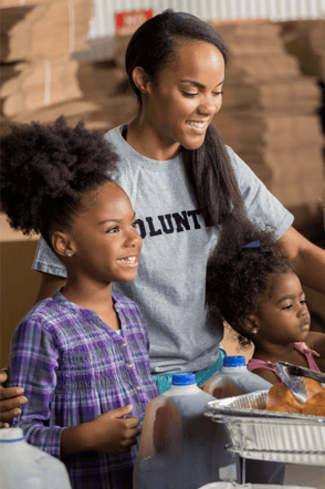 Mother and her two young daughters volunteering in a food kitchen line.